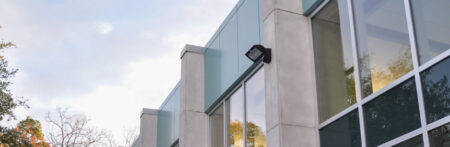 VEK-LED wall light on a white building with large windows.